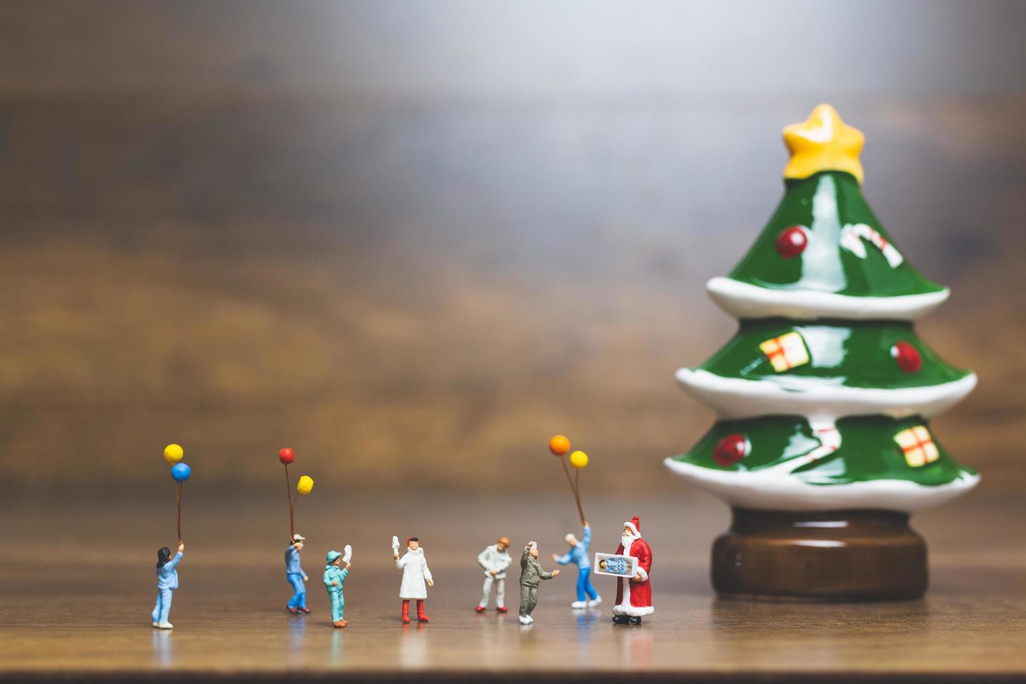 Miniaturfiguren von Menschen, die Weihnachtsschmuck aufstellen foto