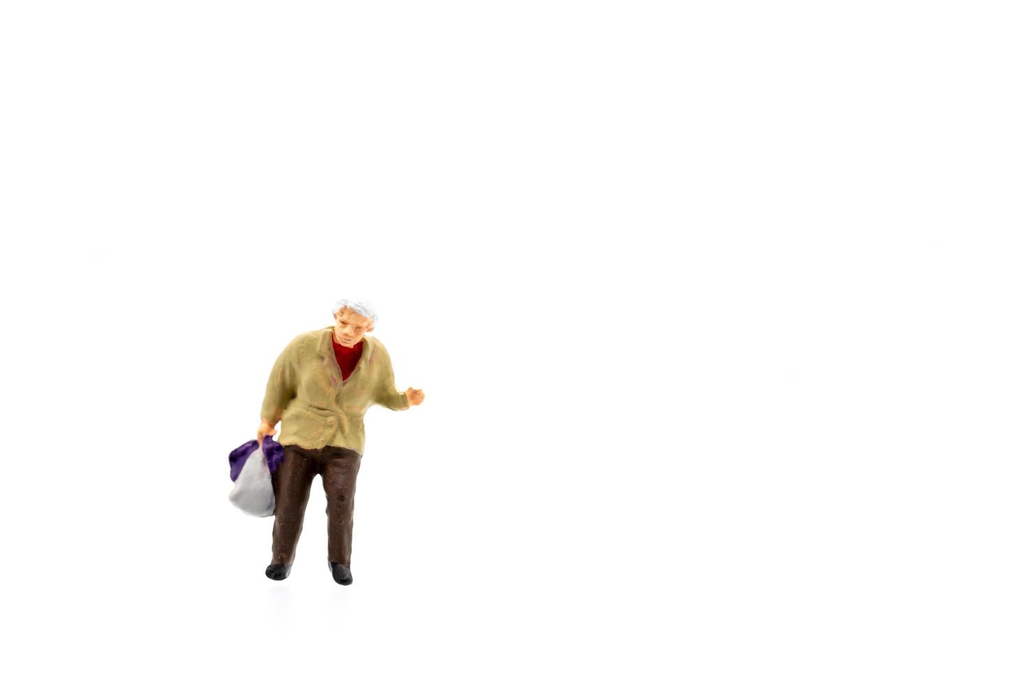 Miniaturfigur einer alten Frau, die auf weißem Hintergrund steht foto