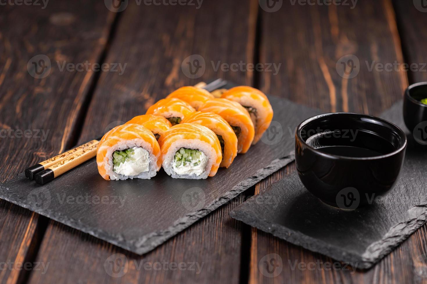 Sushi-Rolle Philadelphia mit Lachs und Gurke und Frischkäse auf schwarzem Hintergrund. Sushi-Menü. japanisches lebensmittelkonzept foto