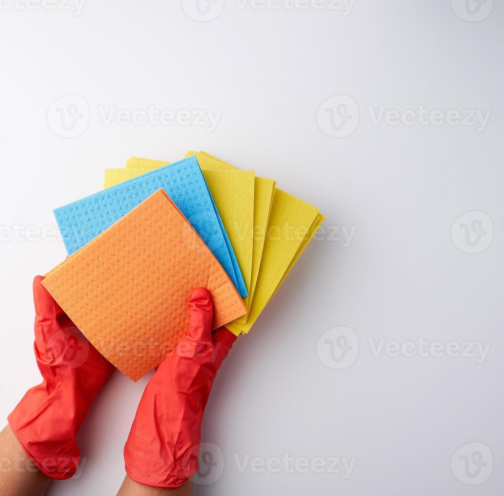 mehrfarbige quadratische saugfähige Schwämme in ihren Händen mit roten Gummihandschuhen foto