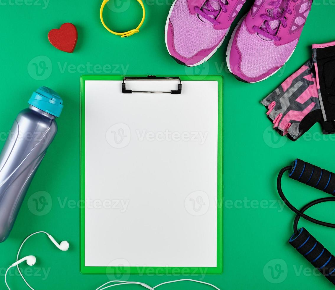 Sport Damenbekleidung für Sport und Fitness, Draufsicht, grüner Hintergrund, in der Mitte der Halter für das Papier foto