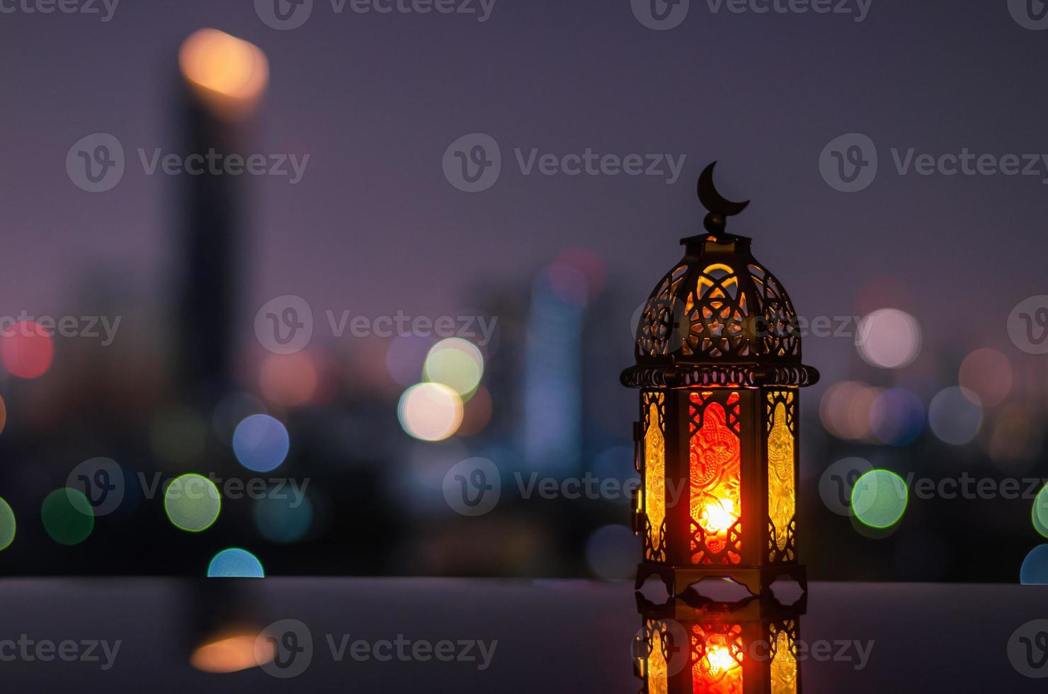 laterne mit dämmerungshimmel und stadt bokeh hellem hintergrund für das muslimische fest des heiligen monats ramadan kareem. foto