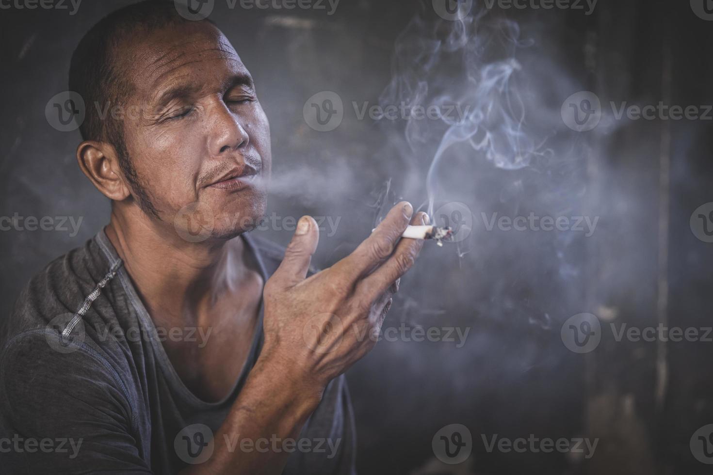 Mann, der eine Zigarette raucht. Zigarettenrauch breitete sich aus. Konzept zur Raucherentwöhnung foto