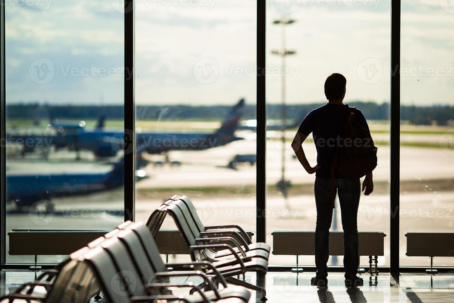 Silhouette eines Mannes, der darauf wartet, einen Flug am Flughafen zu besteigen foto