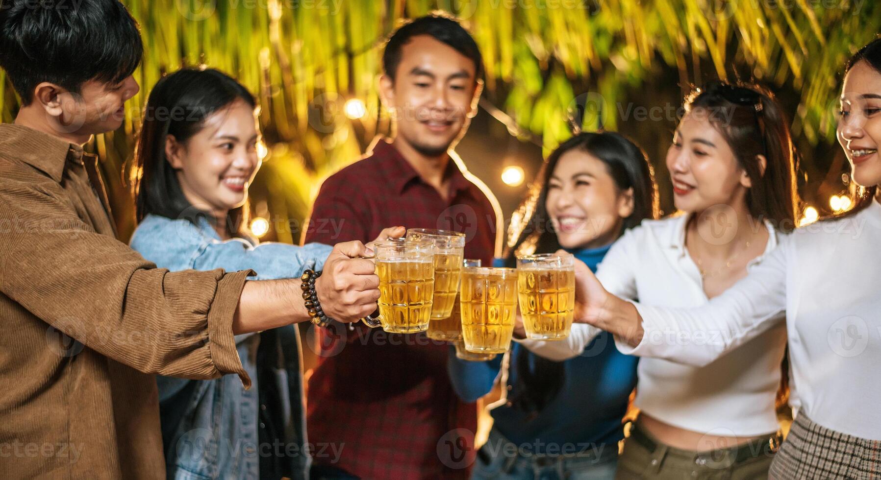 porträt glücklicher asiatischer freunde, die zusammen eine dinnerparty haben - junge leute, die biergläser abendessen im freien anstoßen - menschen, essen, trinken lebensstil, neujahrsfeierkonzept. foto