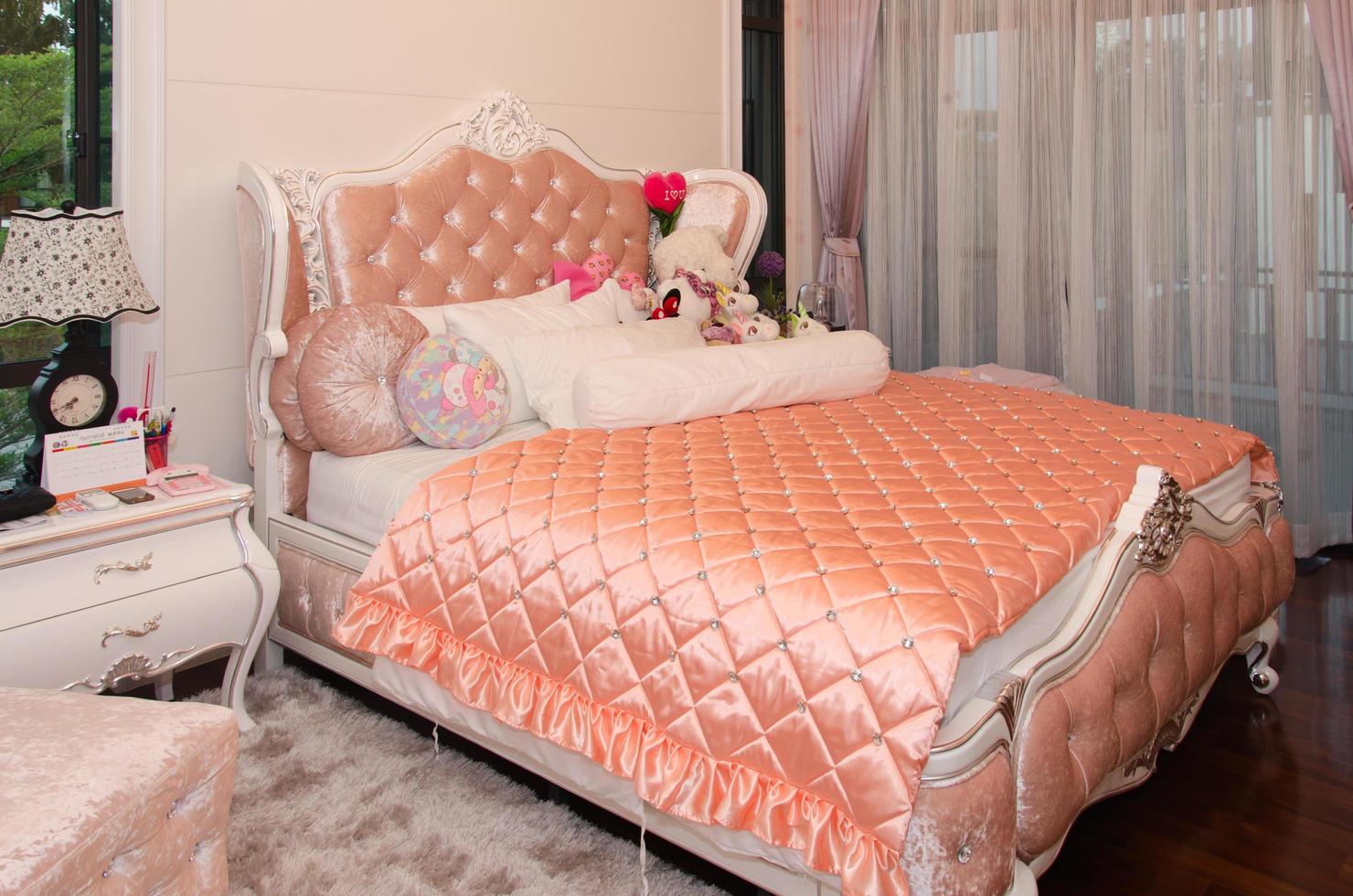 Bett mit rosa Bettdecke und vielen Kissen foto