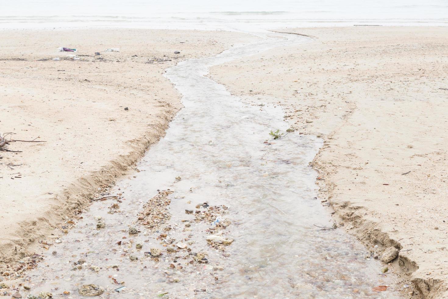 Wasser fließt vom Strand ins Meer foto