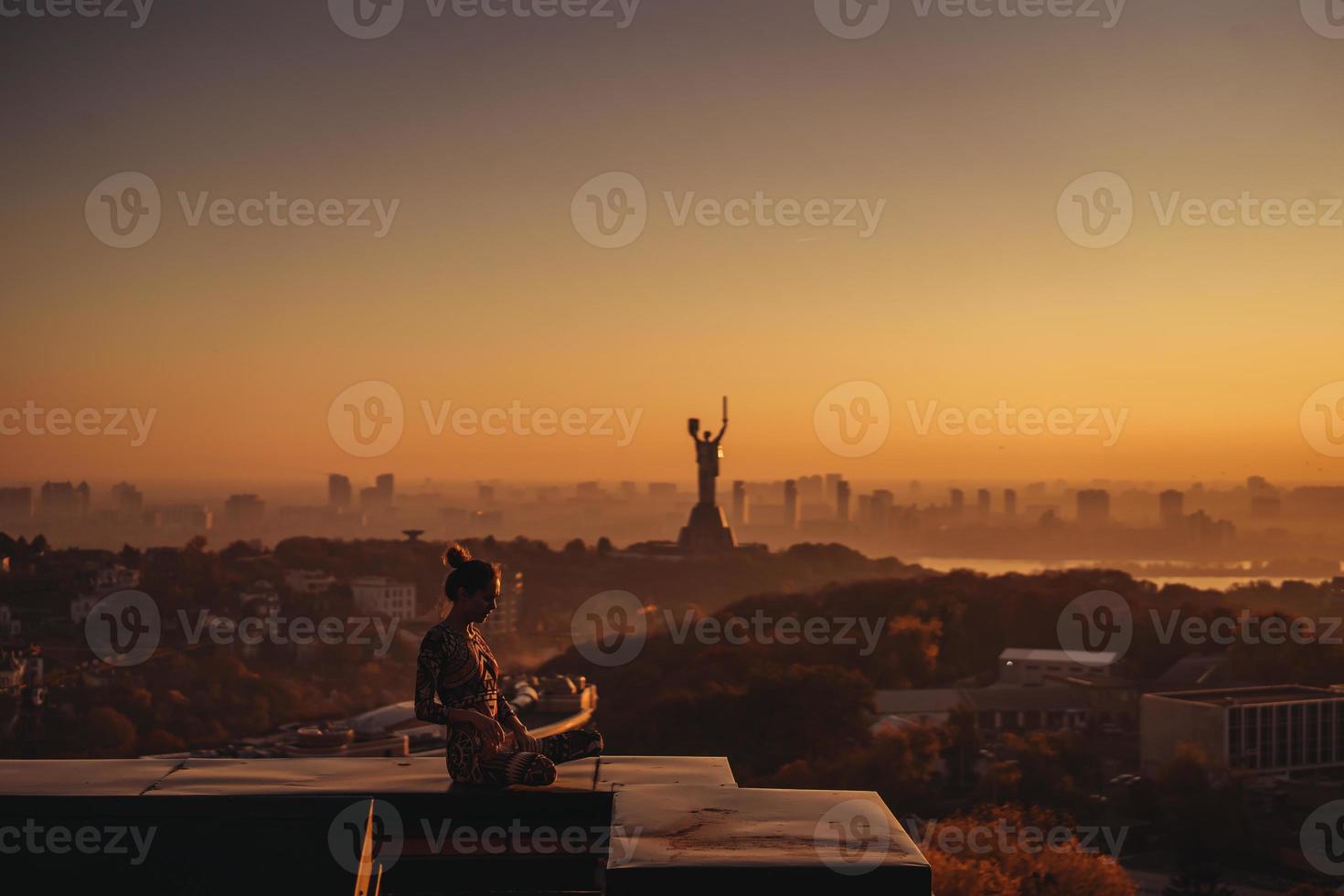 Frau beim Yoga auf dem Dach eines Wolkenkratzers in der Großstadt. foto