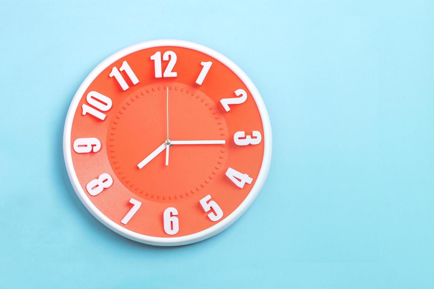 orange Wanduhr auf blauem Hintergrund foto