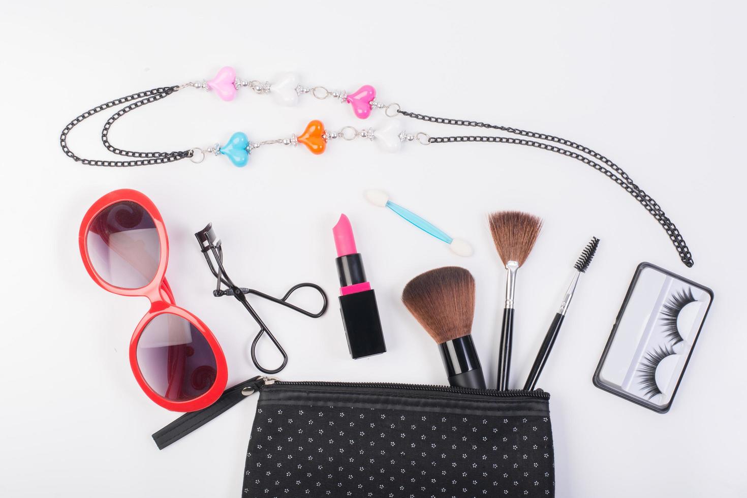 Kosmetiktasche mit Make-up-Sonnenbrille und Halskette lokalisiert auf weißem Hintergrund foto
