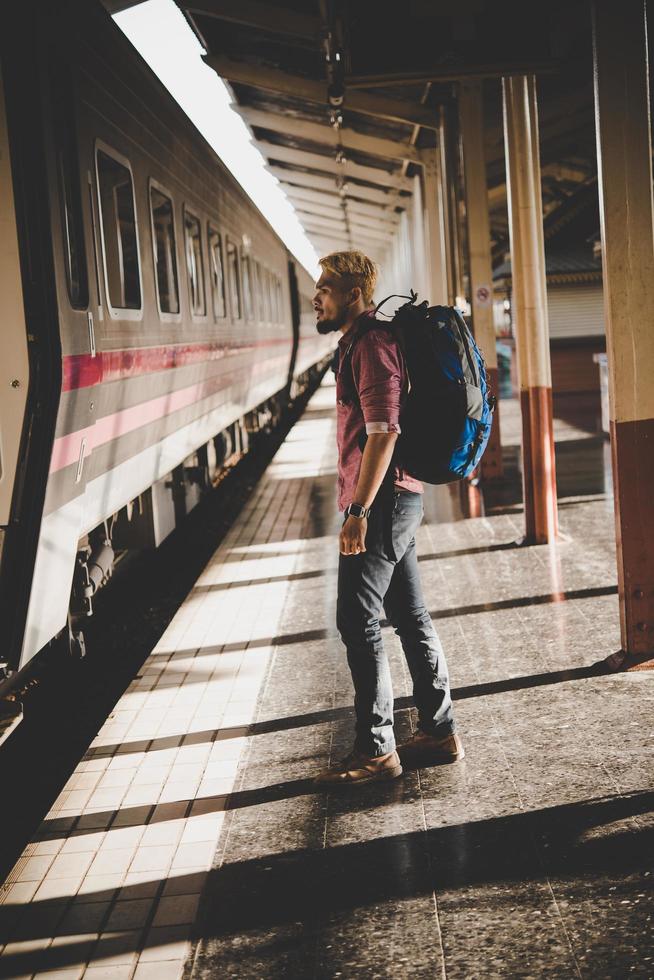 junger Hipster-Tourist mit Rucksack am Bahnhof foto