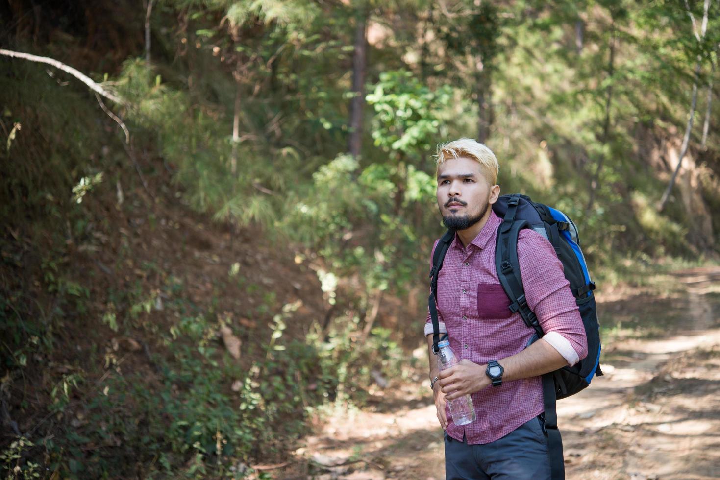 glücklicher Hipstermann-Tourist, der im Naturwald wandert foto