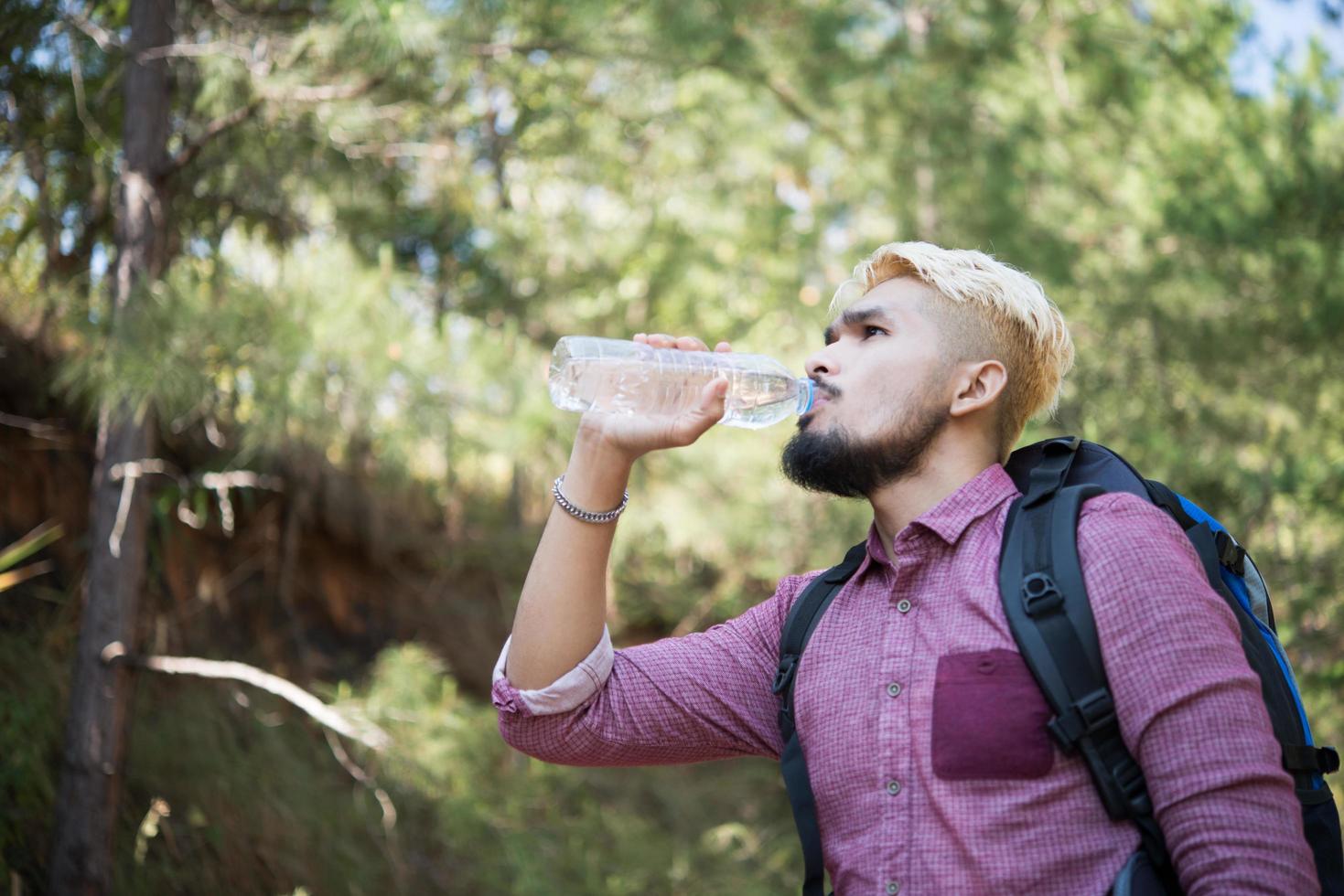 glücklicher Hipster-Mann-Tourist mit Rucksackwandern im Wald foto