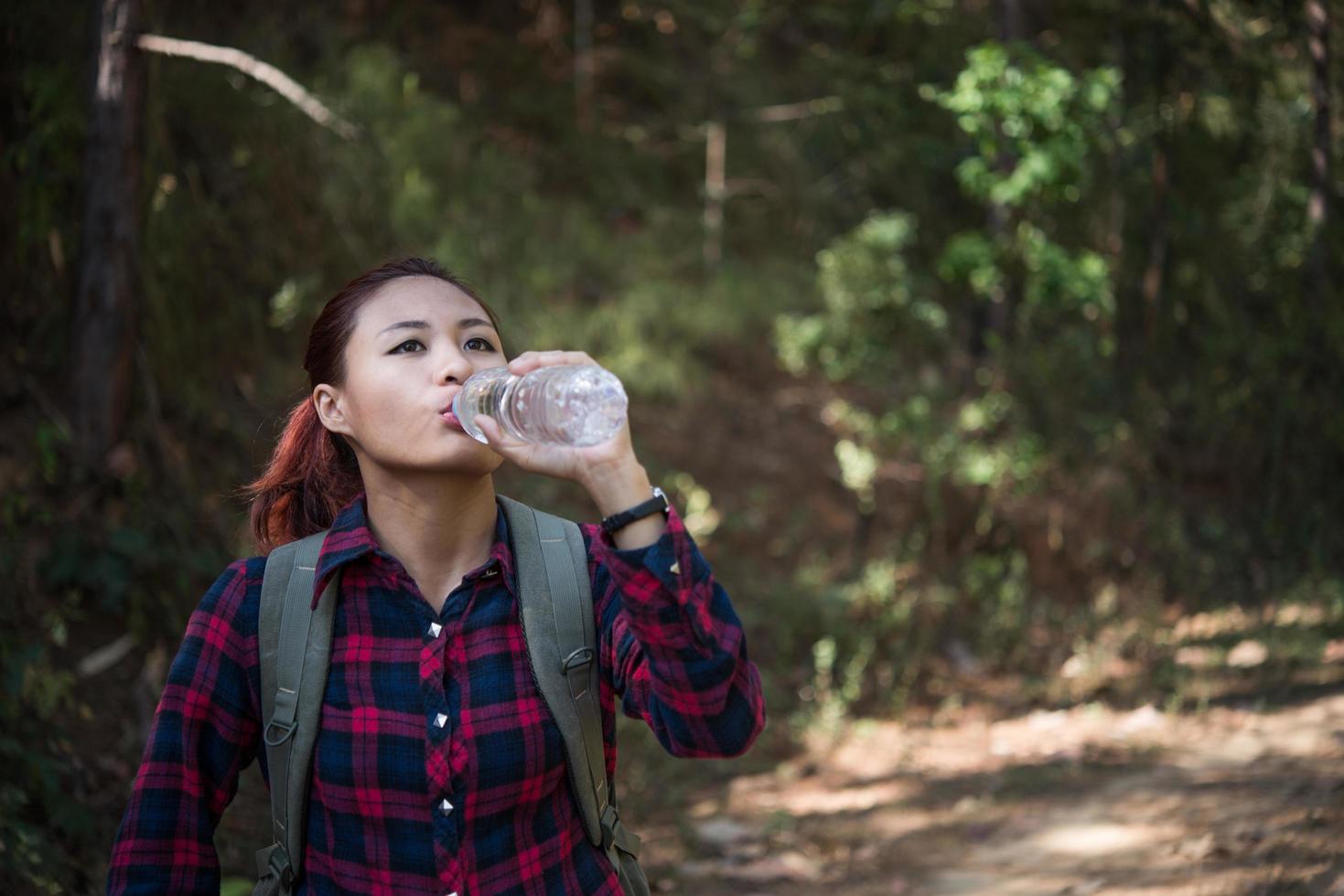 glücklicher Frauentourist mit Rucksacktrinkwasser in der Natur foto