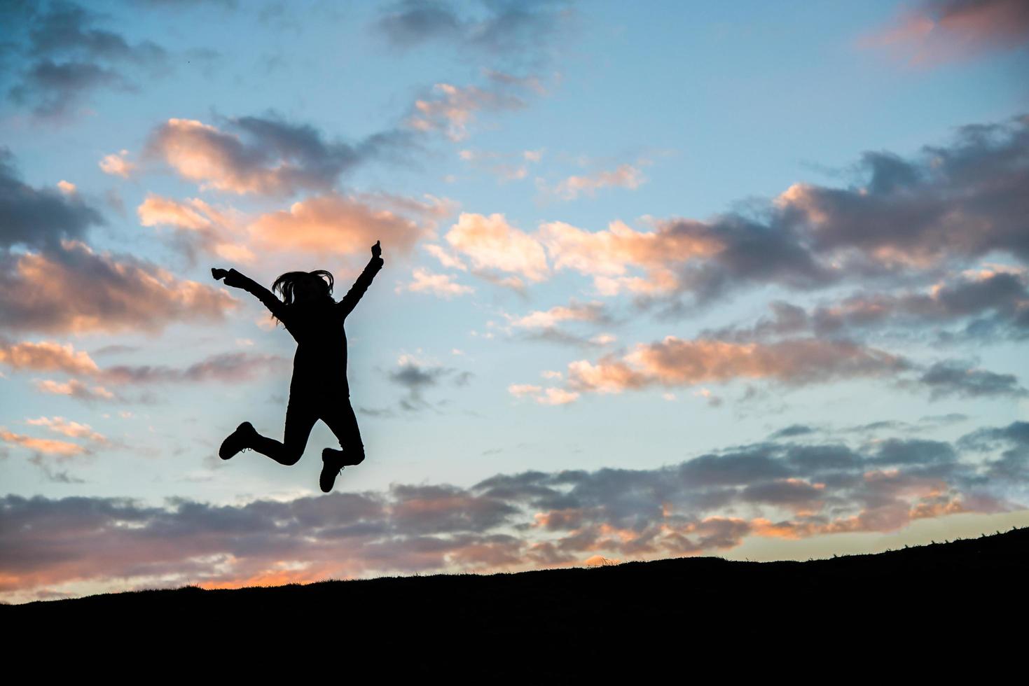 Silhouette einer glücklichen jungen Frau gegen schönen Sonnenuntergang foto