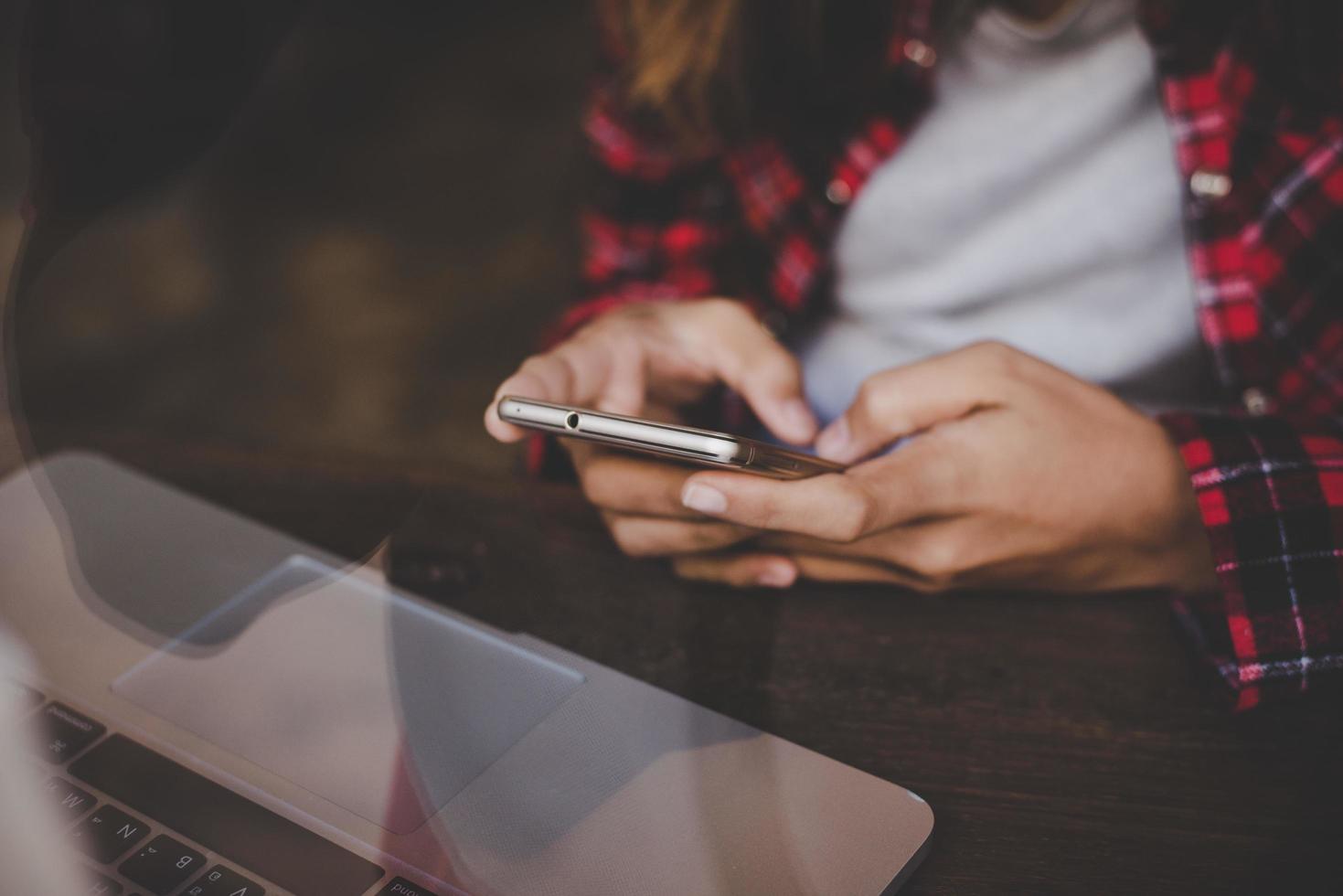 Nahaufnahme einer Frau, die mit ihrem Smartphone in einem Café arbeitet foto