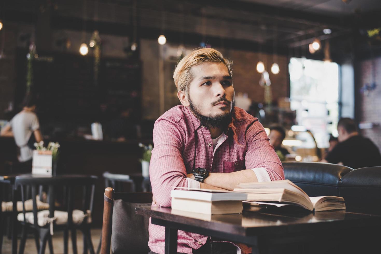 junger bärtiger Hipster, der ein Buch in einem Café liest foto