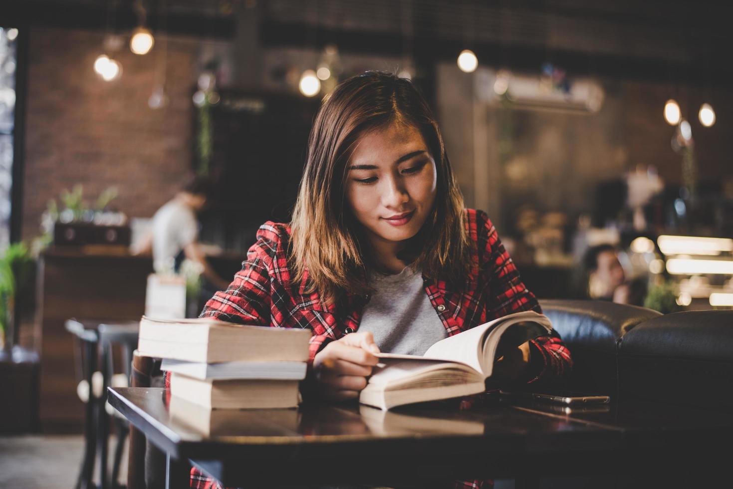 Hipster Teenager sitzt und genießt ein Buch in einem Café foto