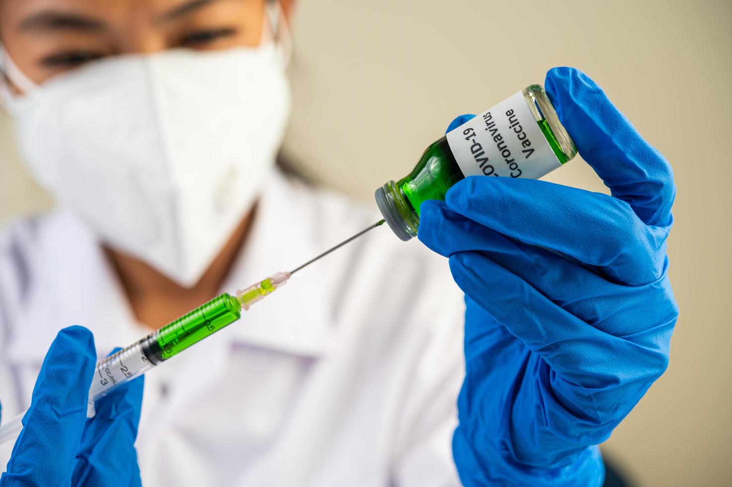 Wissenschaftler tragen Schutzmasken und Handschuhe und halten eine Spritze mit einem Impfstoff, um Covid-19 zu verhindern foto