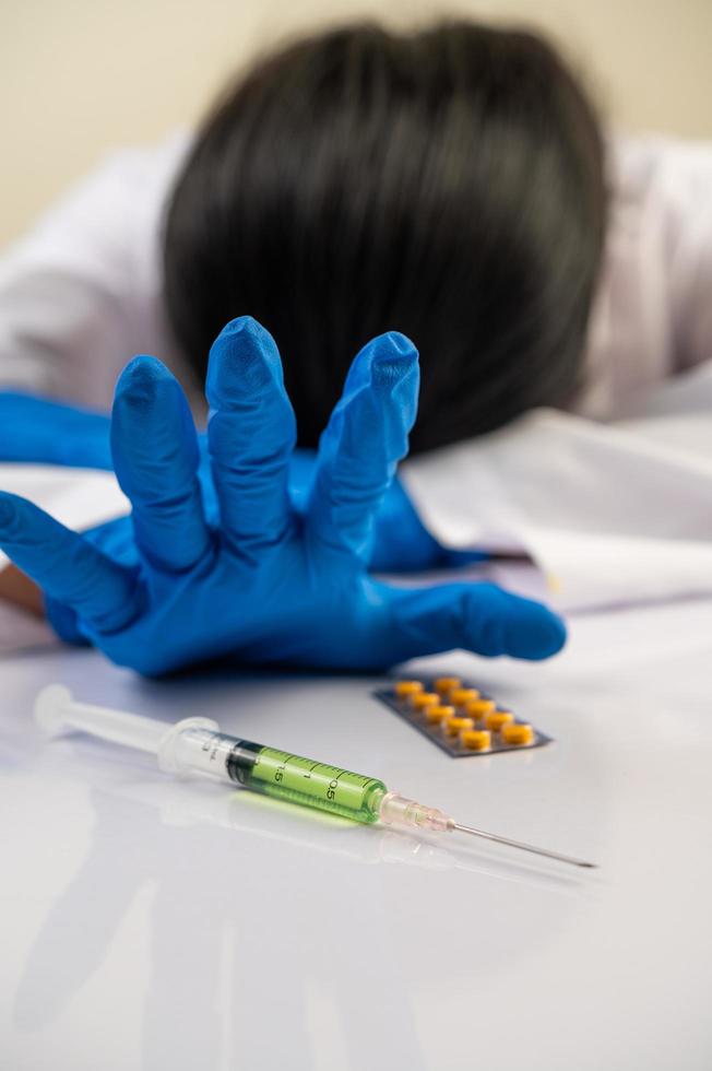 Wissenschaftler am Tisch mit Impfstoffen und Drogen foto