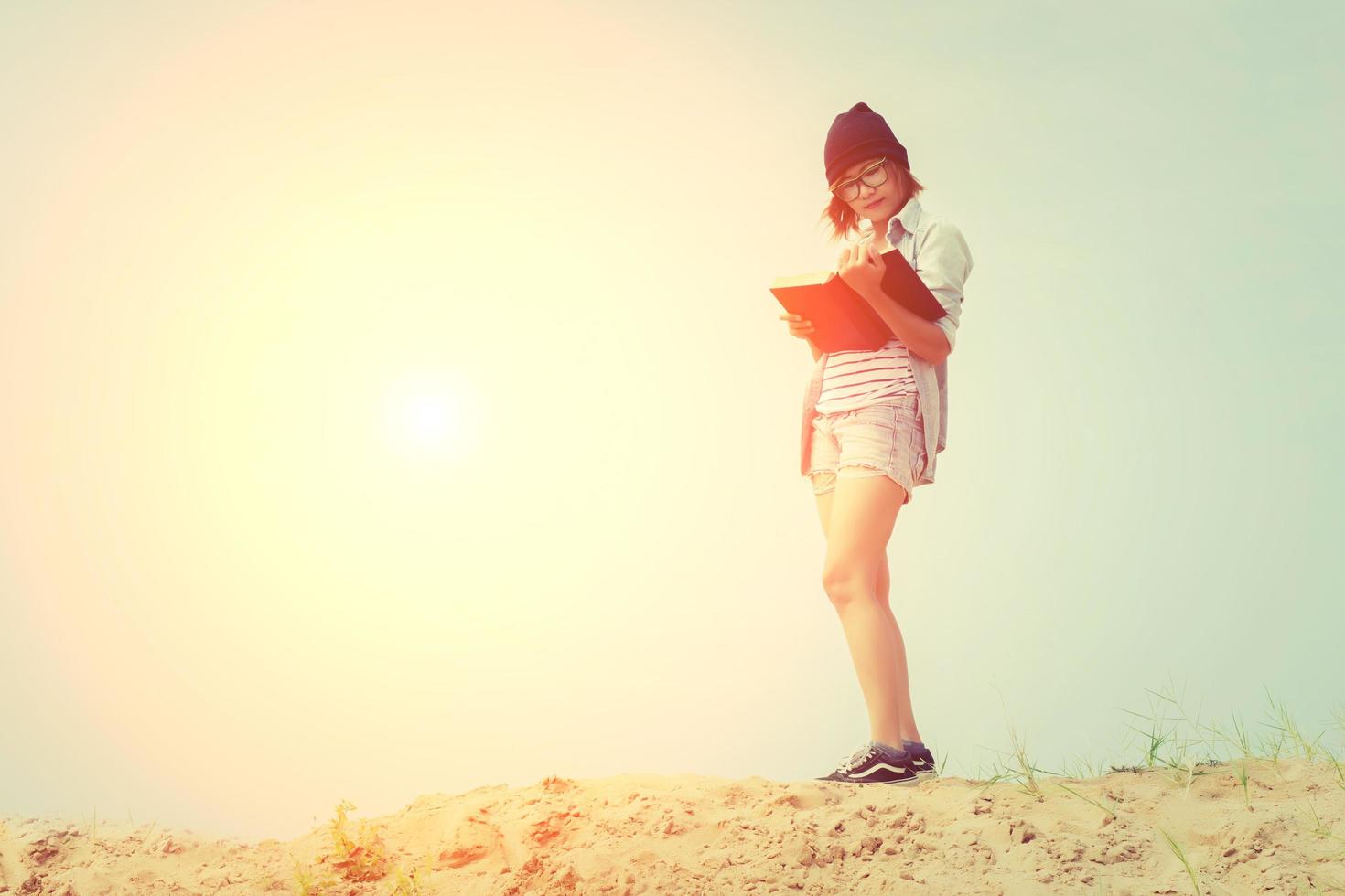 schöne junge Frau, die ein Buch am Strand liest foto