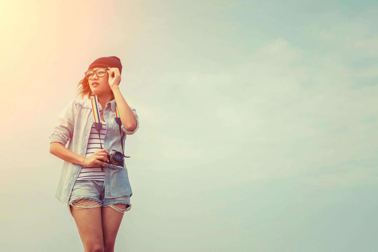 schöne Frau, die Brille mit einer Retro-Kamera trägt foto