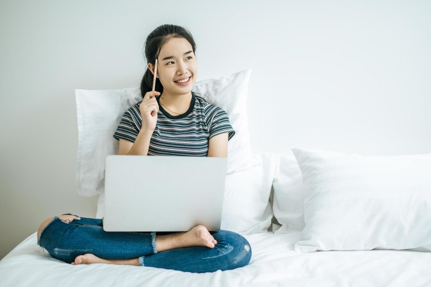 junge Frau spielt auf ihrem Laptop und hält einen Bleistift foto