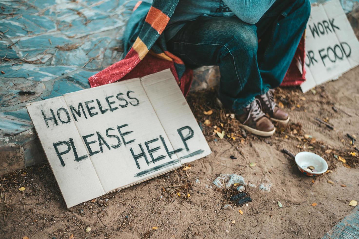 Ein Mann sitzt und bettelt mit Obdachlosen. Bitte helfen Sie foto