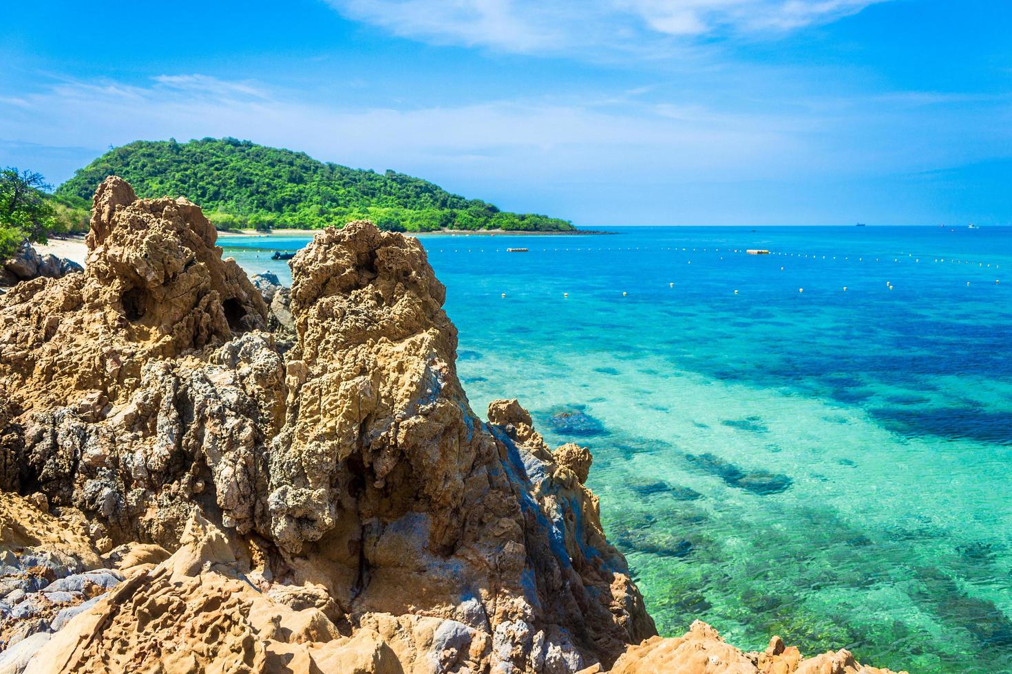 tropischer Inselfelsen am Strand mit bewölktem blauem Himmel foto