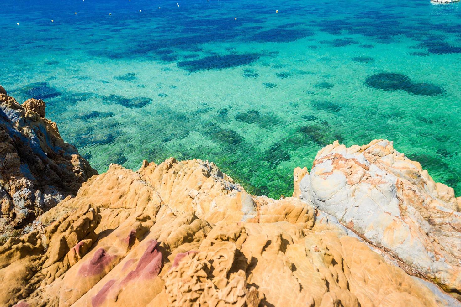 tropischer Inselfelsen am Strand mit klarem blaugrünem Wasser foto