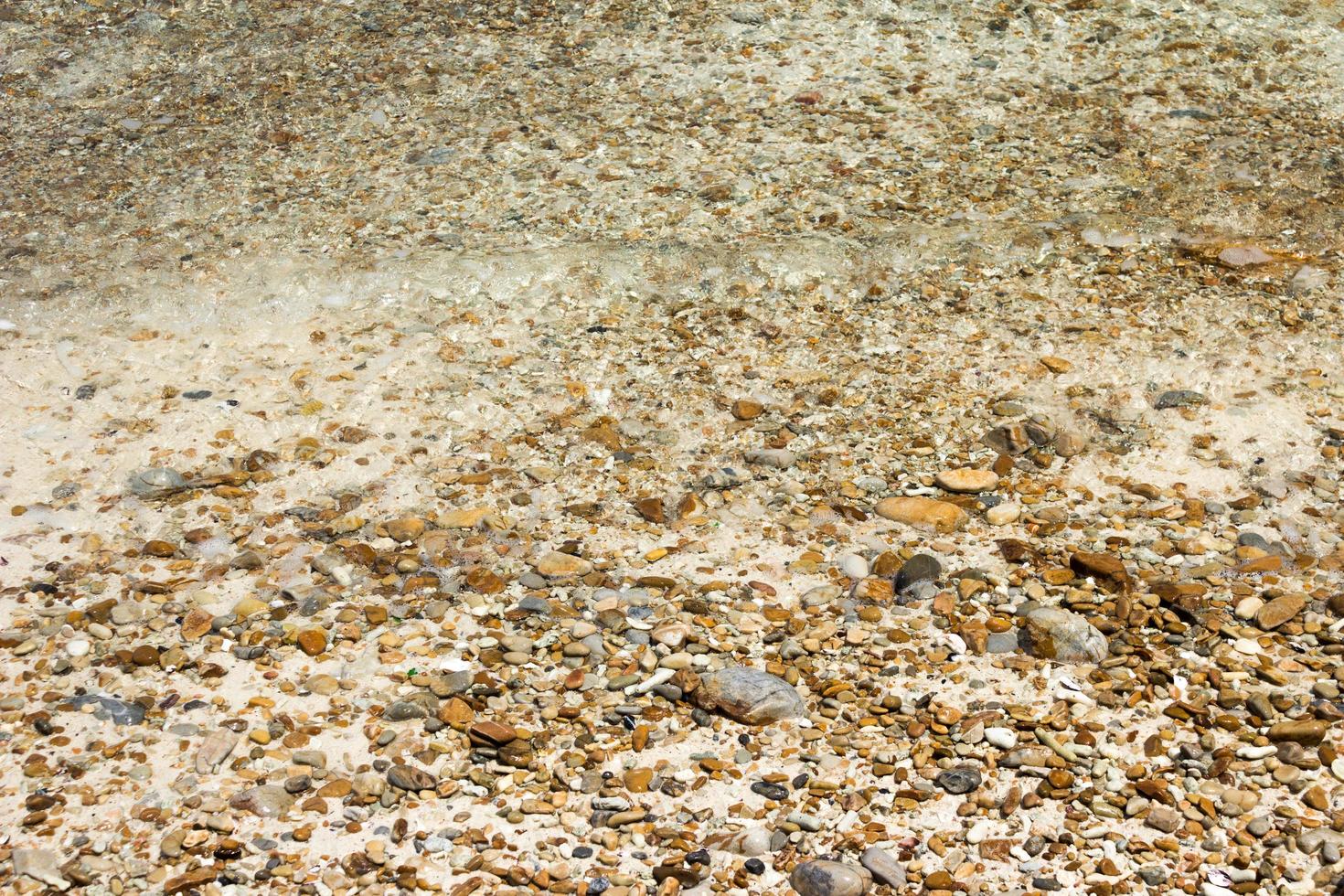 Wasser auf Kieselsteinen am Strand foto