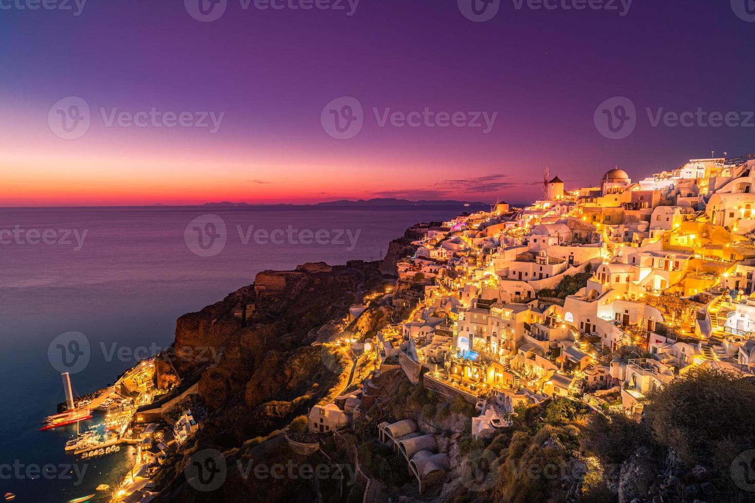 schöne aussicht auf das fabelhafte malerische dorf oia mit traditionellen weißen häusern und windmühlen auf der insel santorini bei nacht, griechenland. berühmtes sommerferien- und ferienziel, sonnenuntergangslandschaft foto