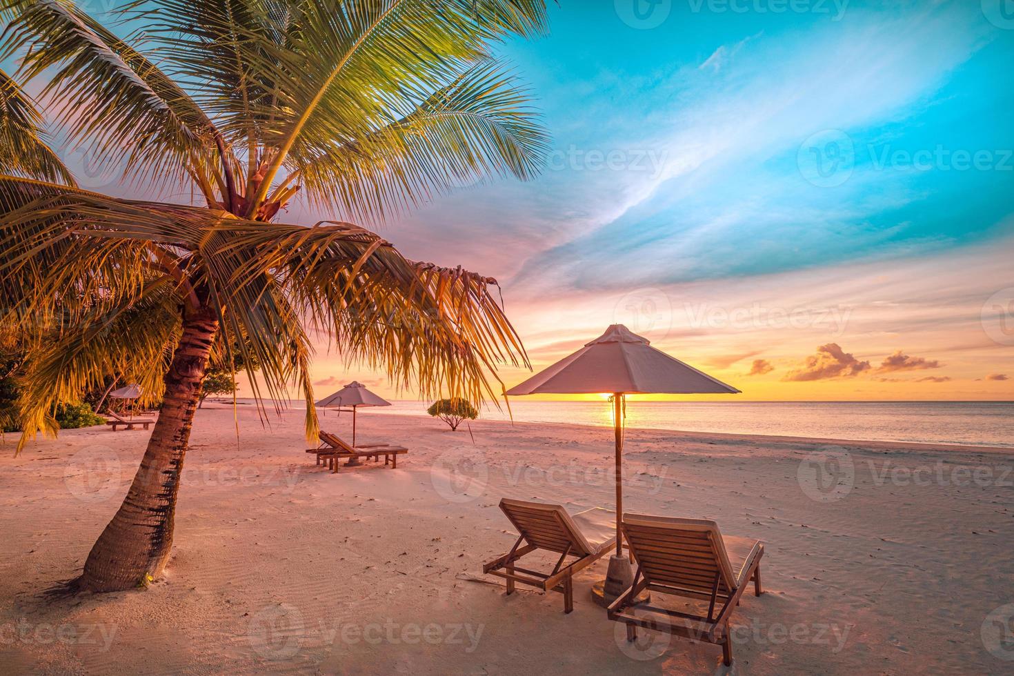Wunderschöner tropischer Sonnenuntergangsstrand, ein paar Sonnenliegen, Sonnenschirme unter Palmen. weißer Sand, Meerblick mit Horizont, bunter Dämmerungshimmel, Ruhe und Entspannung. inspirierendes Strandresort-Hotel foto
