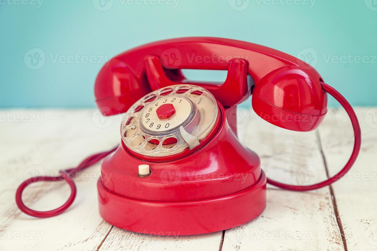 Rotes, buntes Vintage-Telefon über einem weißen Holztisch foto