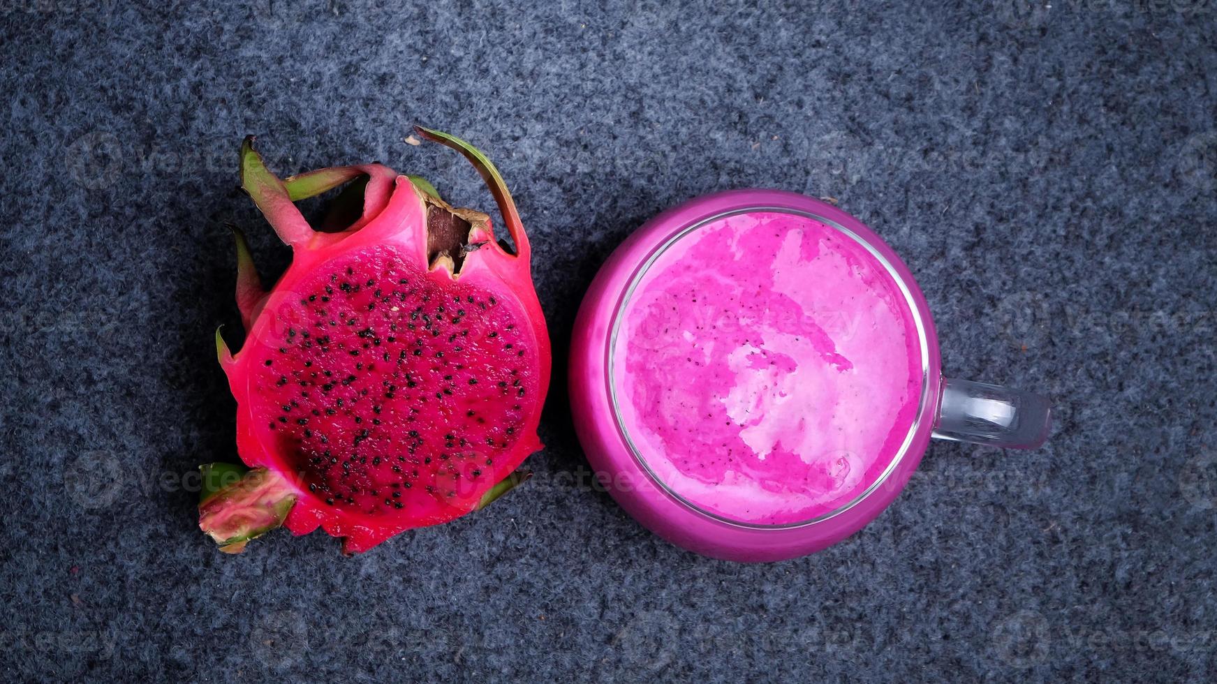 Draufsicht auf ein Glas Drachenfruchtsaft mit einer Scheibe frischer Drachenfrucht auf dunklem Hintergrund. gesundes getränkekonzept foto