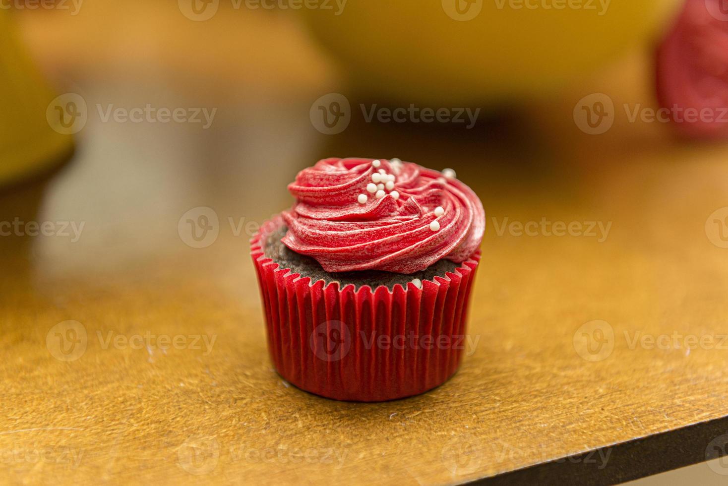 leckerer Schokoladen-Cupcake mit roter Sahneglasur und Streuseln. foto