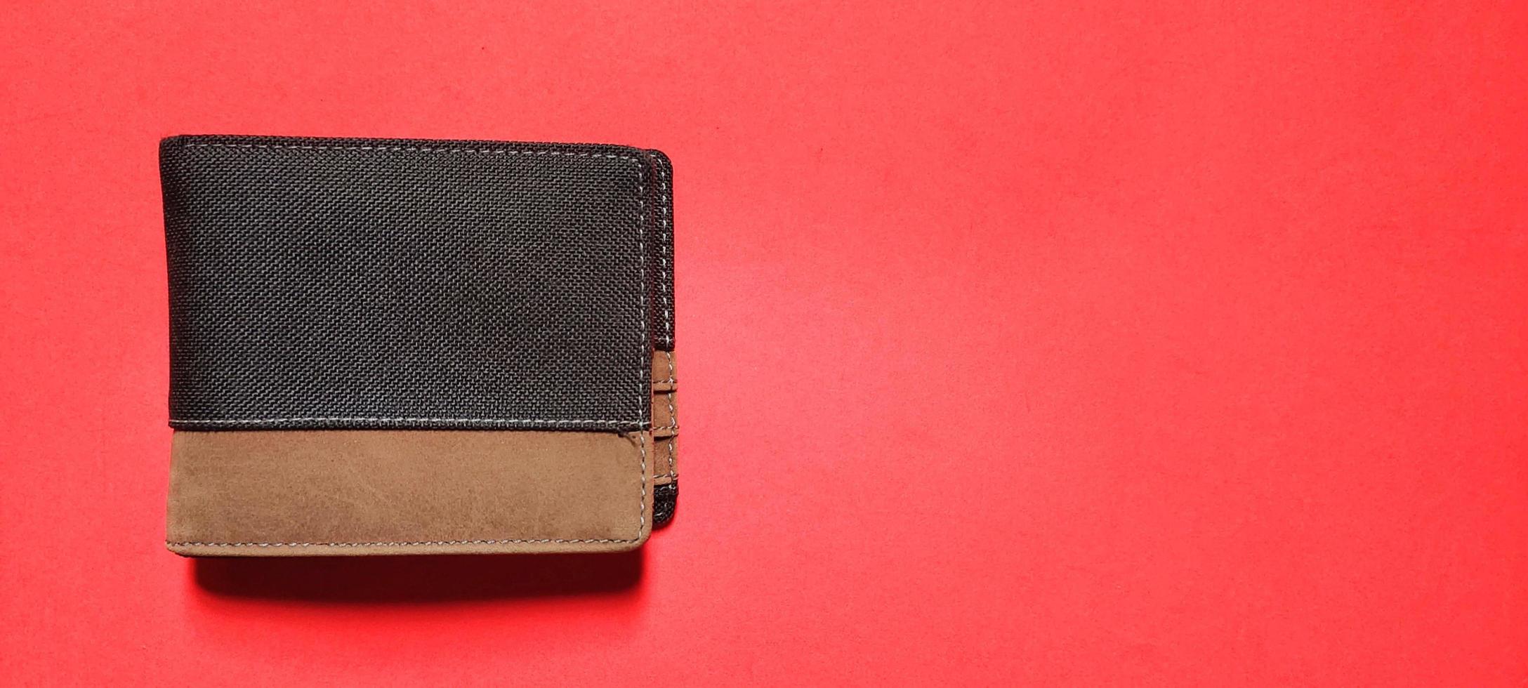Blick von oben auf die schwarze und braune Brieftasche, isoliert auf rotem Hintergrund. negativer Raum foto