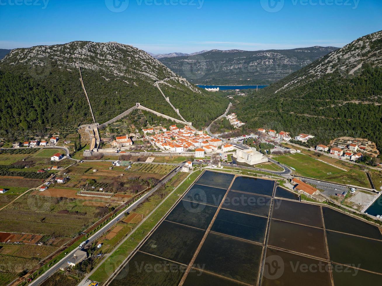 luftdrohnenansicht der salzpfanne in der stadt ston in kroatien. Festungsmauern in den Hügeln im Hintergrund. Salzfelder. Salzwerke Stein. tourismus in der nähe der adria. historische Besuche. foto