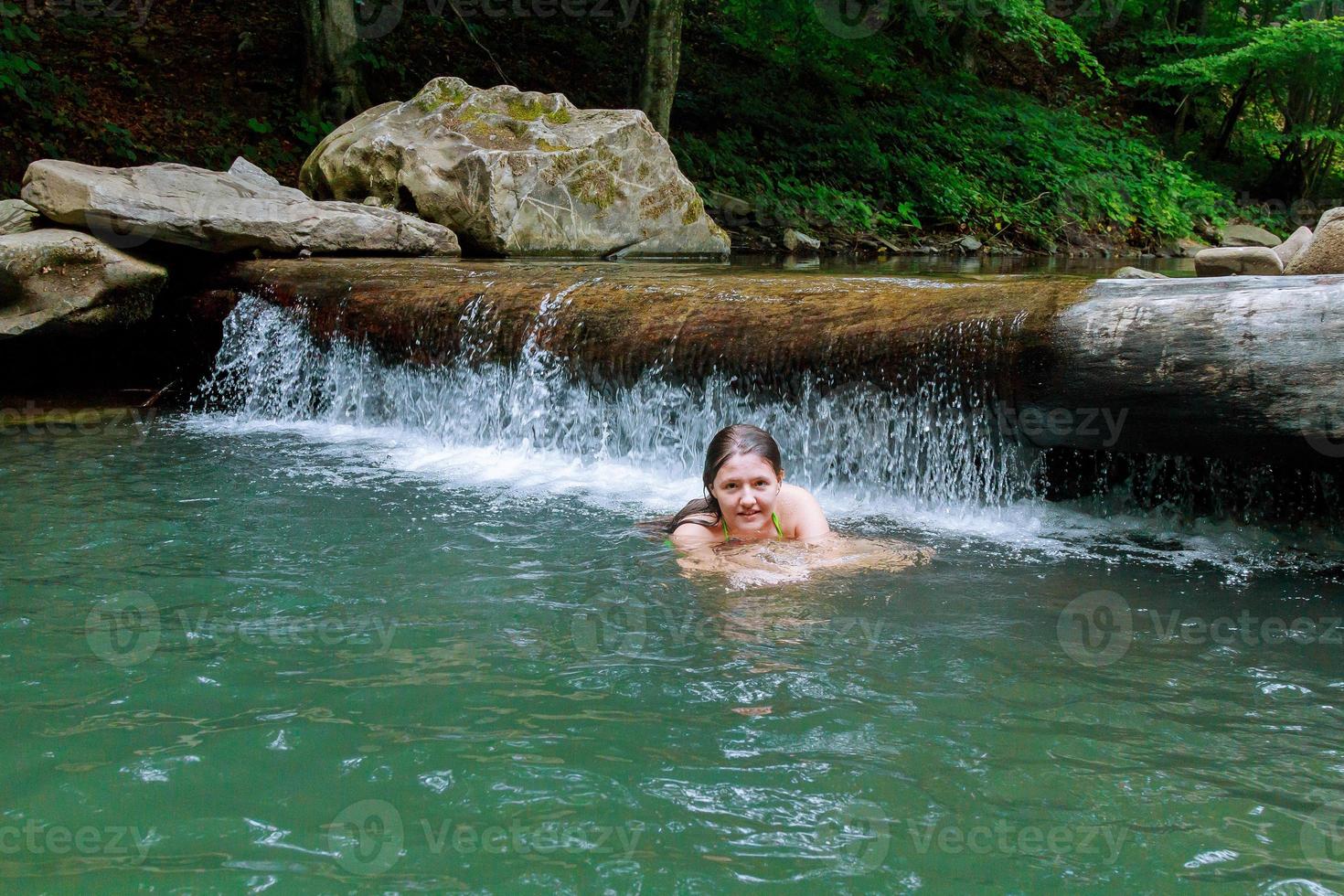 schönes Mädchen, das im Fluss schwimmt foto