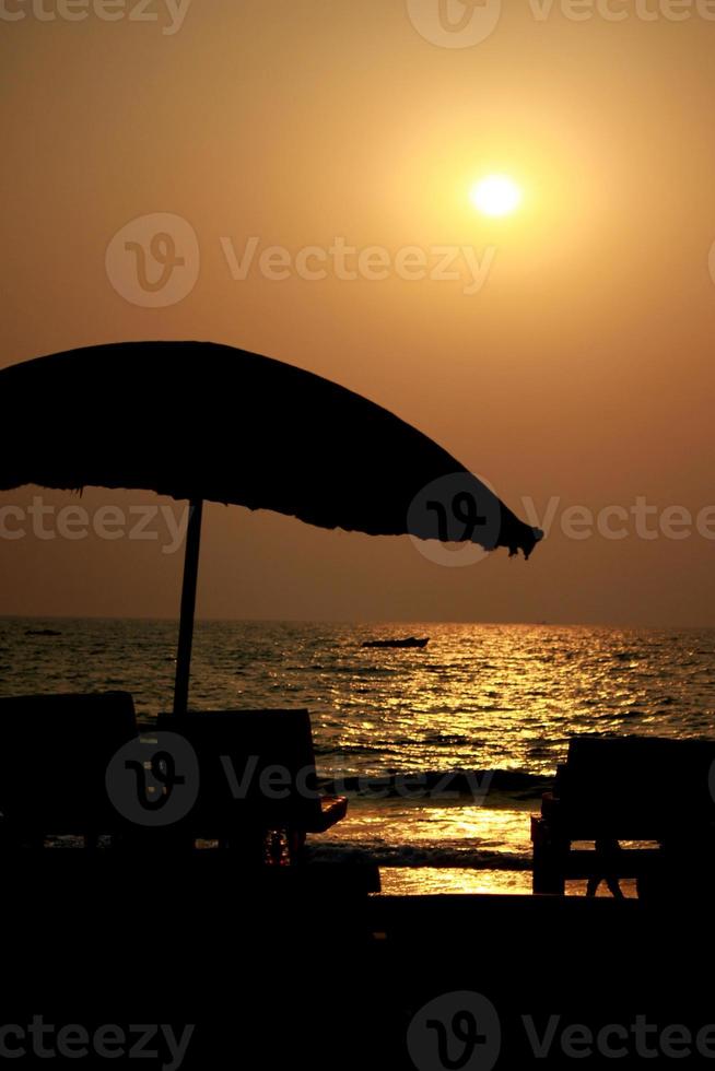 Sonnenuntergangsstrand mit Sonnenschirm foto