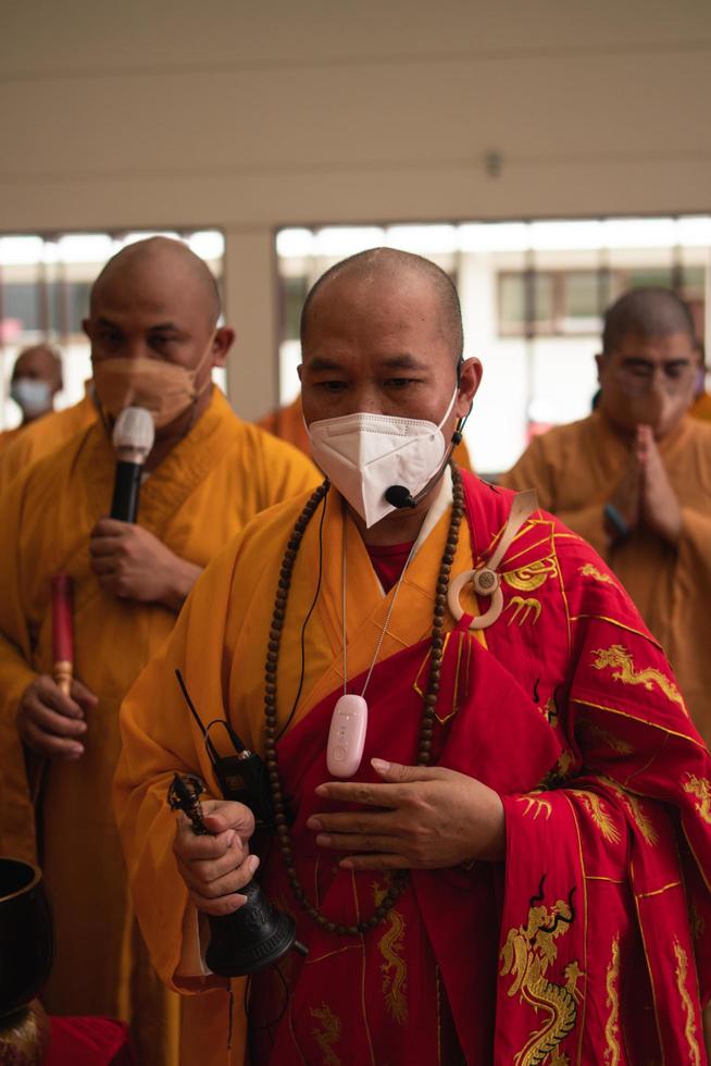 Bandung, Indonesien, 2020 - eine Gruppe von Mönchen mit orangefarbenen und roten Gewändern, die gemeinsam am Altar beten foto