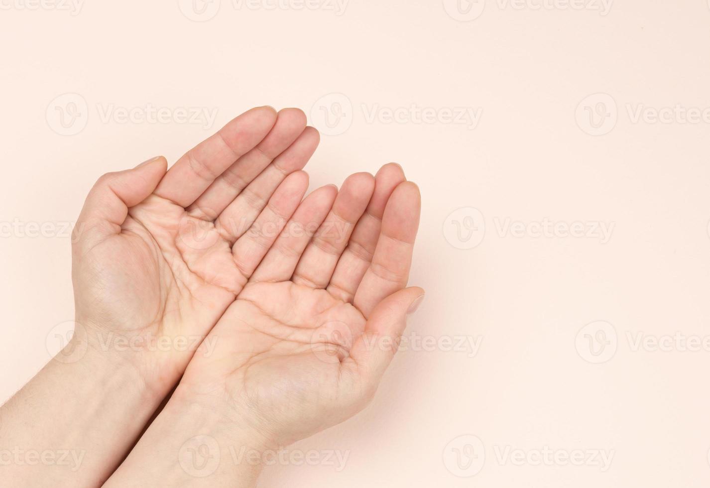 Zwei weibliche Hände falteten sich von Handfläche zu Handfläche auf einem beigen Hintergrund foto