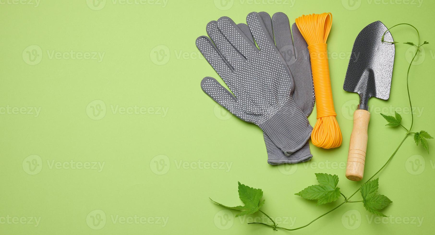 gartengeräte für die verarbeitung von beeten im garten und textilhandschuhe auf grünem hintergrund foto