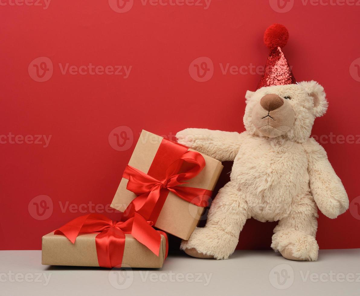 Teddybär in einem roten festlichen Hut hält ein rosa Blatt Papier foto