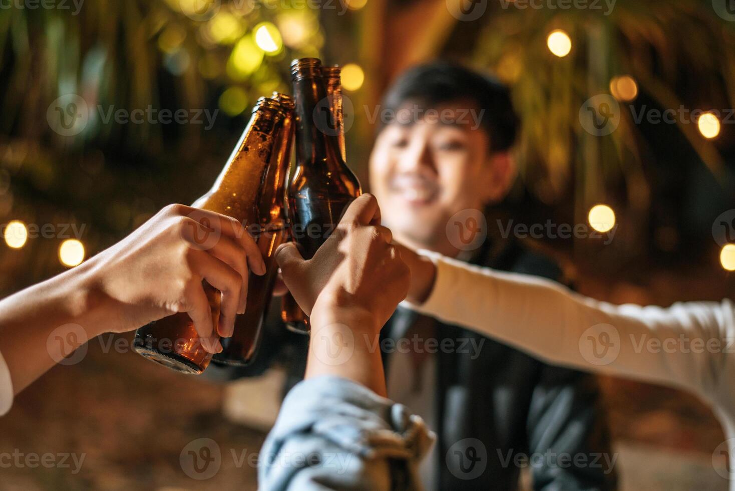 porträt glücklicher asiatischer freunde, die zusammen eine dinnerparty haben - junge leute sitzen am bartisch und toasten biergläser abendessen im freien - leute, essen, trinken lebensstil, neujahrsfeierkonzept. foto