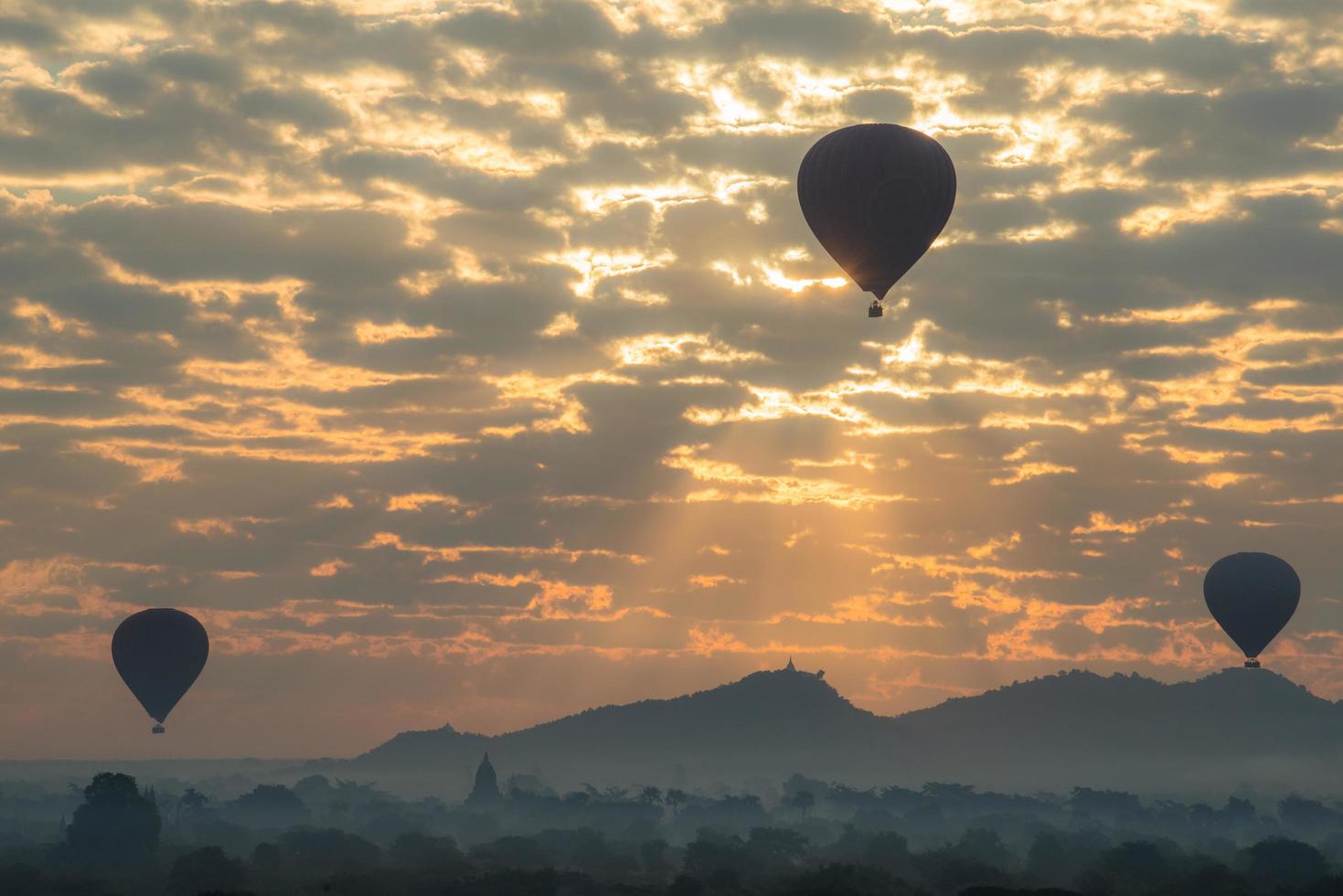 heißluftballons, die während des sonnenaufgangs in der archäologiezone von bagan, mandalay-region von myanmar, über die bagan-ebene fliegen. foto