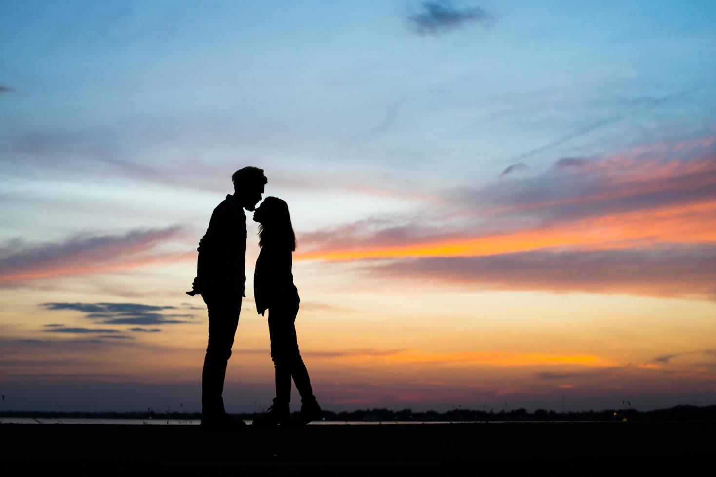 Silhouette des jungen Paares zusammen während des Sonnenuntergangs foto