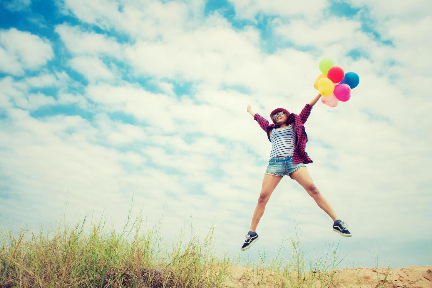 schönes Mädchen, das mit Luftballons am Strand springt foto