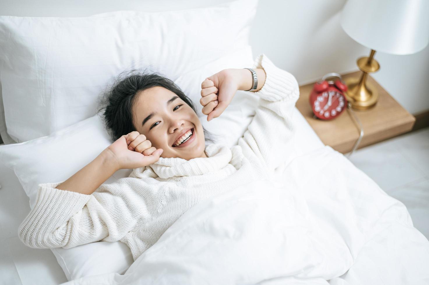 junge Frau, die weißes Hemd trägt, das gerade im Bett aufwacht foto