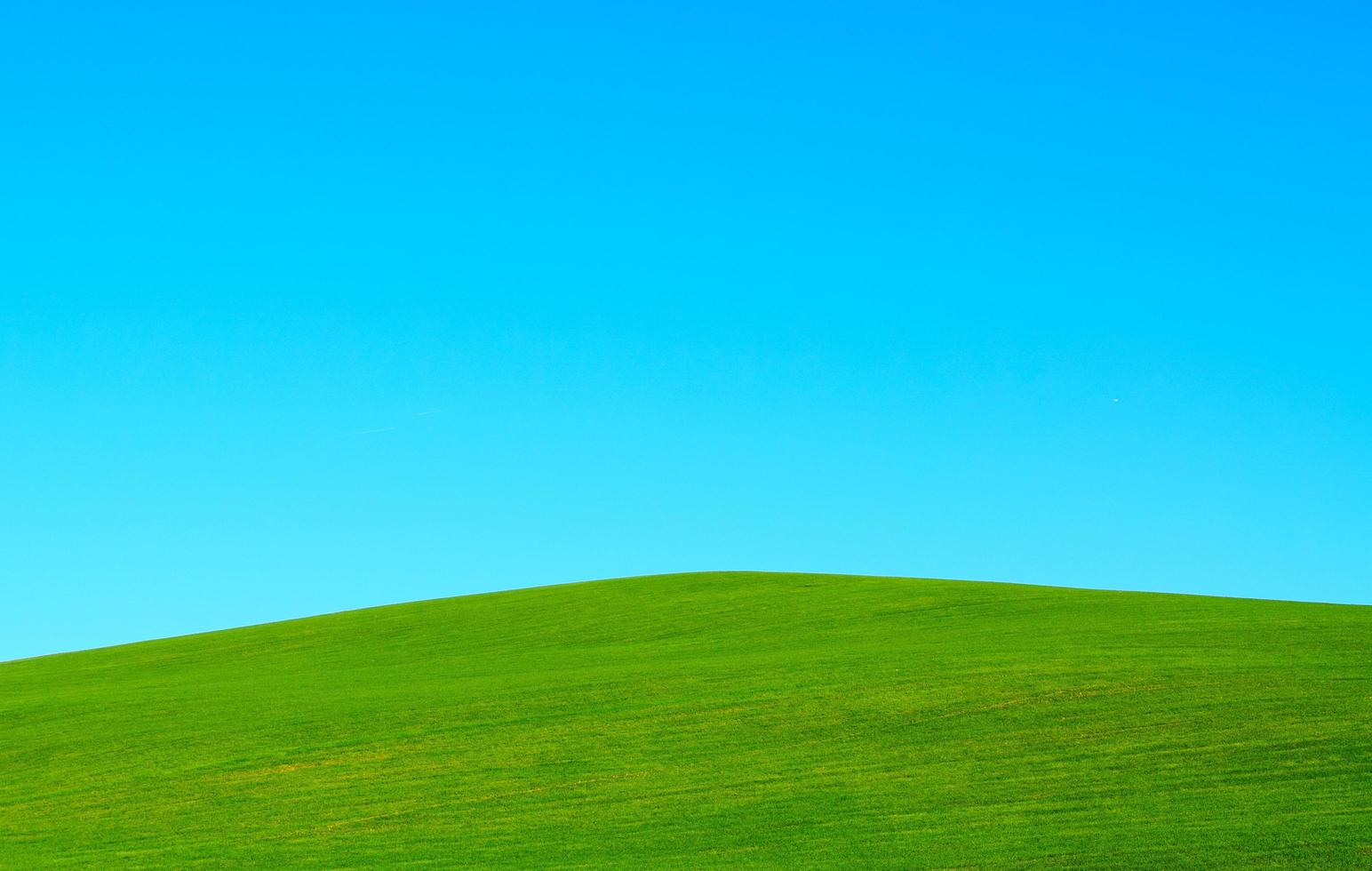 grüner Hügel unter klarem blauem Himmel foto